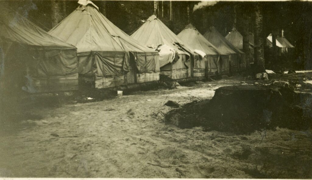 a row of world war I army tents stand along a path made of sawdust