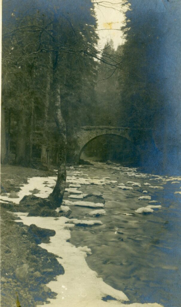 stone bridge over Vologne River which has snow on its banks