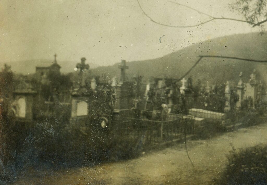 village cemetery in France with stone crosses and mountains in the background