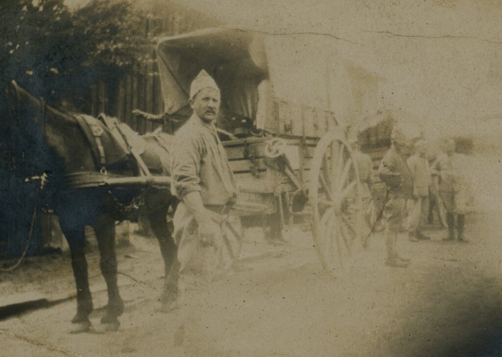 a man wearing a hat stands next to a covered buggy